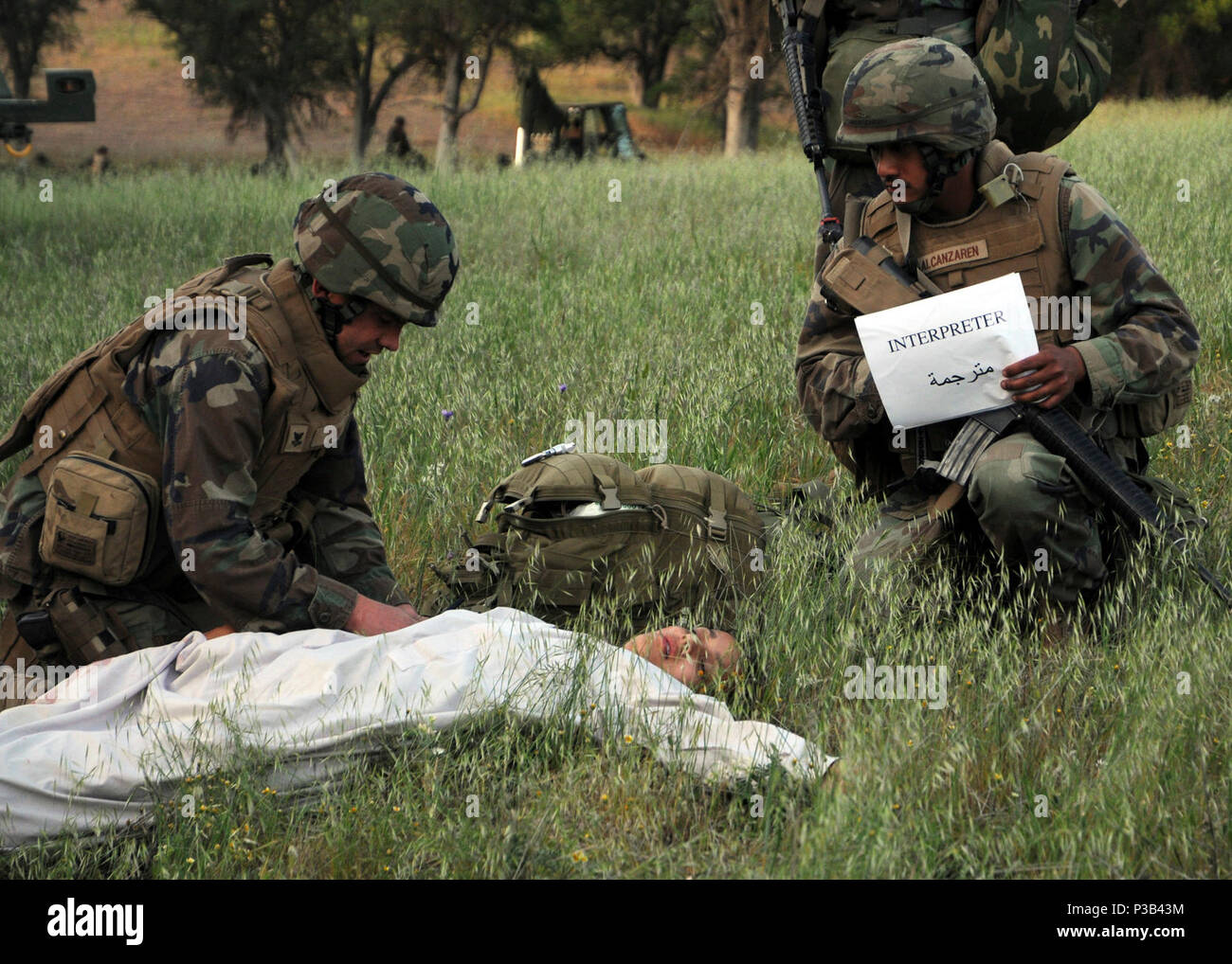 HUNTER LIGGETT, Calif. (April 22, 2009) Hopspital Corpsman 2nd Class Damian Young, assigned to Naval Mobile Construction Battalion (NMCB) 3, and his interpreter, Construction Electrician 2nd Class Frantel Alcanzaren, treat a civilian with a simulated injury during Operation Bearing Duel 2009. Bearing Duel is an annual field training exercise to test the battalion's ability to deploy to a contingency environment. Stock Photo