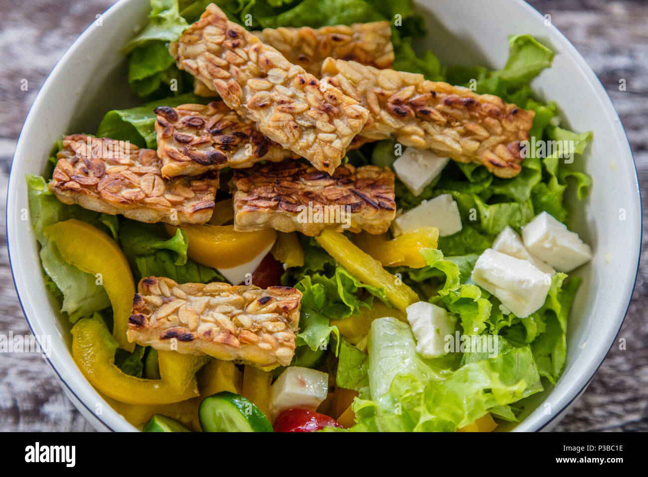 Raw vegetable and lettuce salad with organic lettuce, capsicum, tomato, cucumber, feta cheese and tempe goreng - fried tempeh. Bali Island, Indonesia Stock Photo