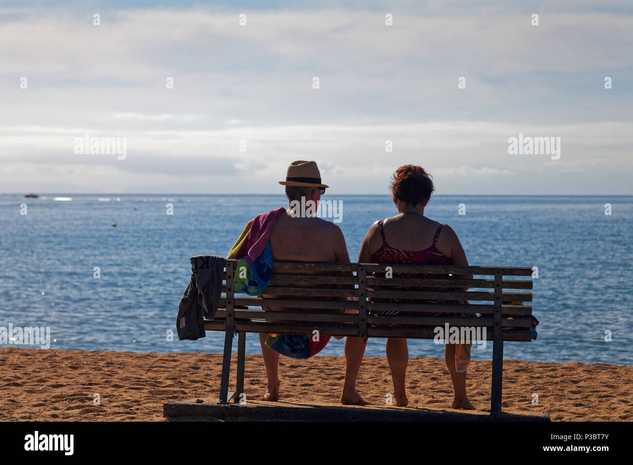 older couple enjoying sitting looking at the sea after a day on the beach Stock Photo