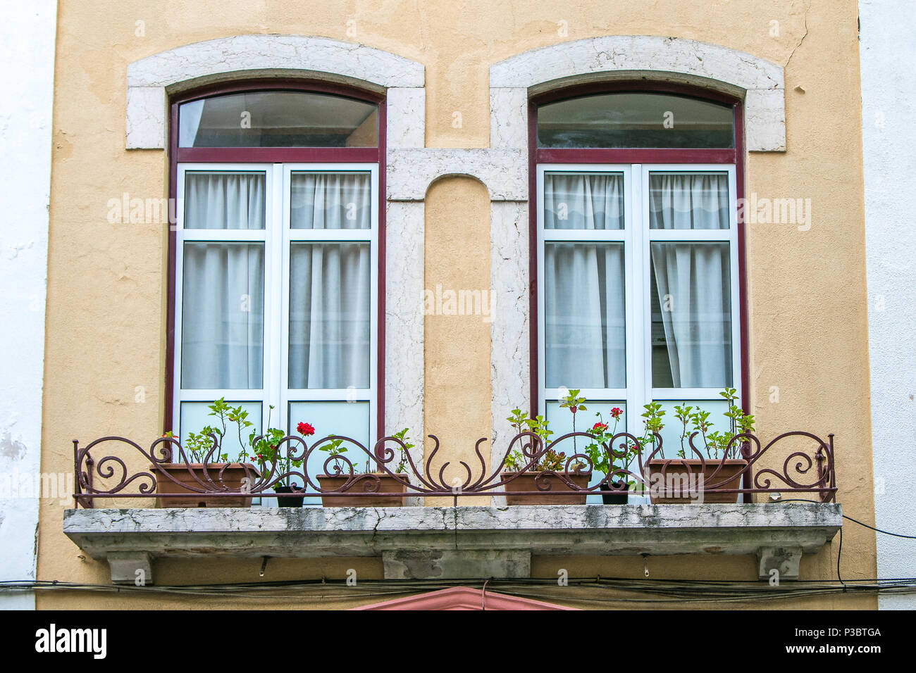 Paired arched windows with a balcony housing flower pots. European architecture. Stock Photo