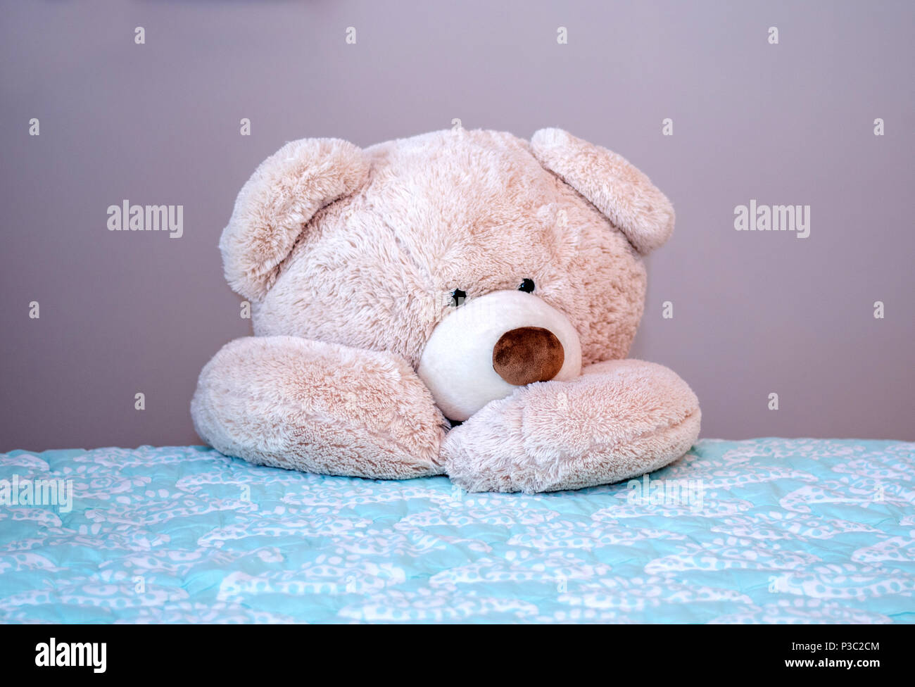 Big teddy bear kneels beside the bed for evening prayers Stock Photo