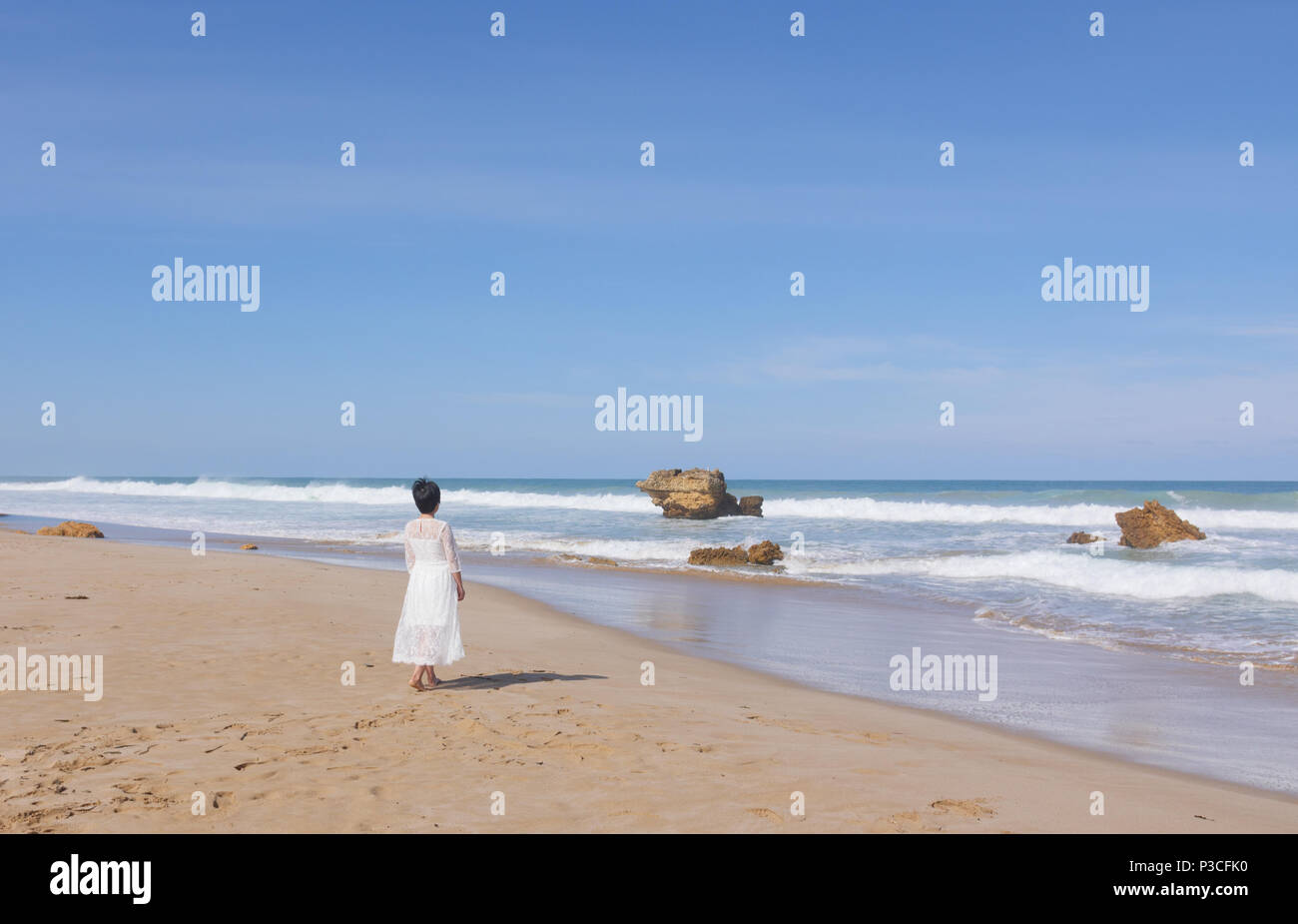 Girl in wedding dress running along the beach Stock Photo