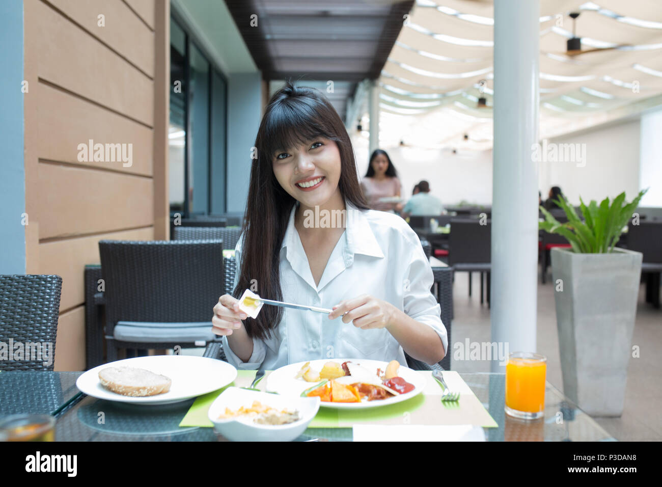 Young beautiful girl enjoy and relaxing  her breakfast in the outdoor atmosphere restaurant, Thailand Stock Photo