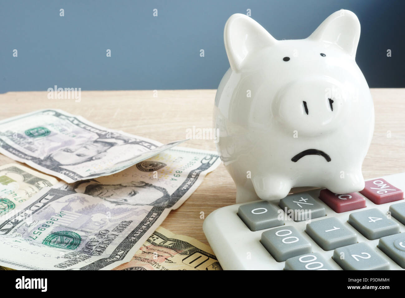 Money worries concept. Unhappy piggy and few banknotes with calculator. Problems with money. Stock Photo