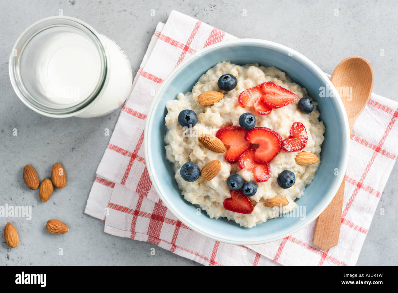 Oatmeal porridge with fresh berries and nuts in a bowl top view. Healthy lifestyle, healthy eating, dieting, fitness and vegetarian food concept Stock Photo