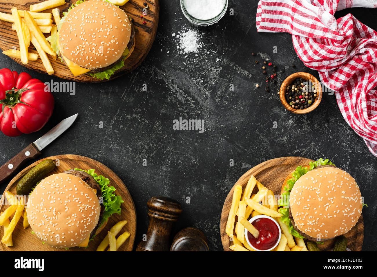 Burgers and french fries on dark stone background, top view with copy space. Homemade hamburgers and fries. Fast food or BBQ concept Stock Photo