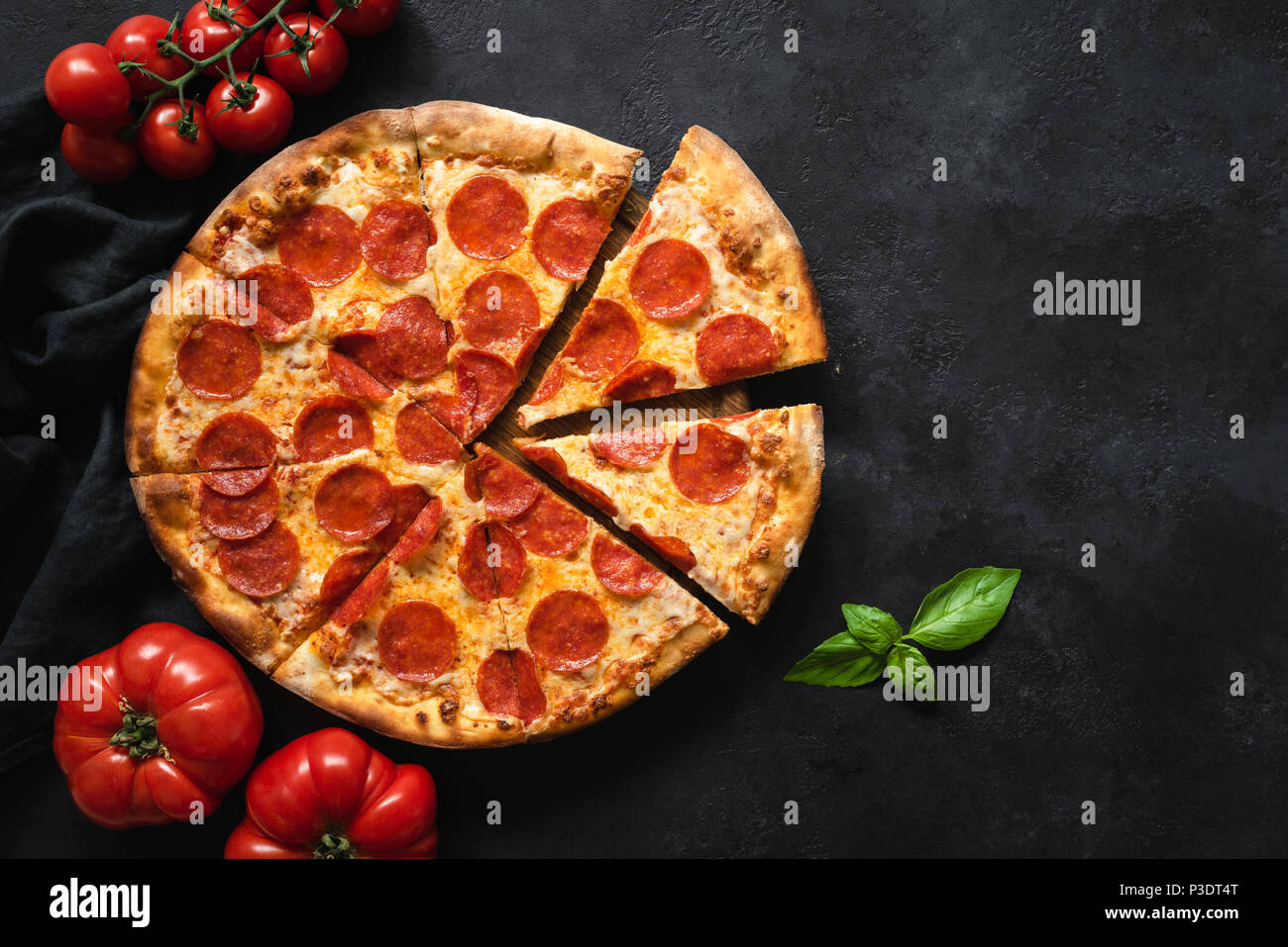 Pepperoni pizza on black concrete background. Top view with copy space. Tasty sliced pepperoni pizza Stock Photo