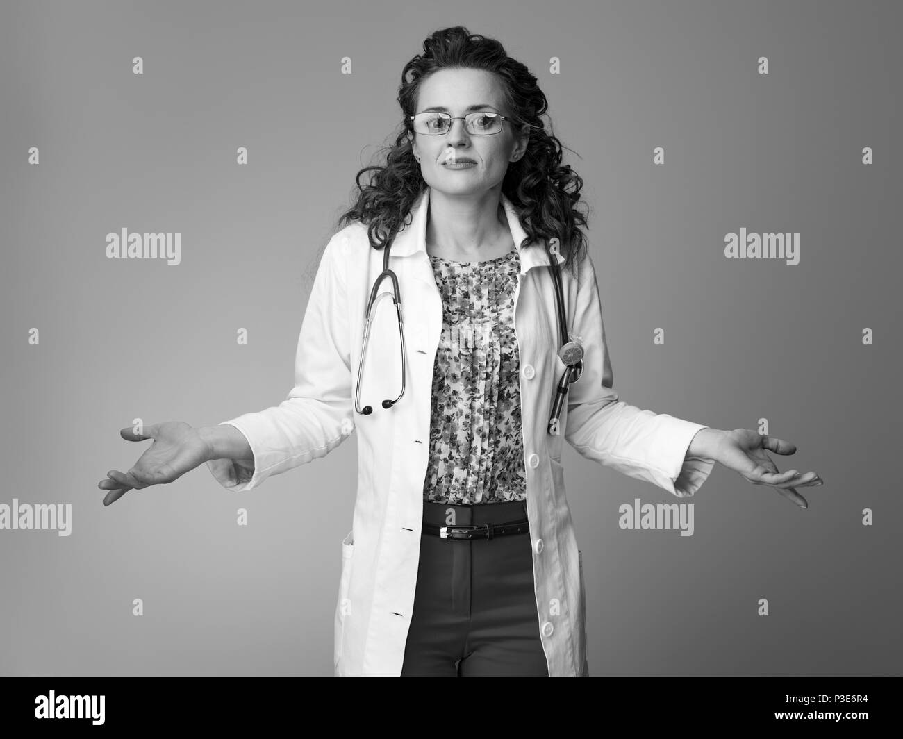 paediatrist doctor in white medical robe shrugging shoulders on background Stock Photo