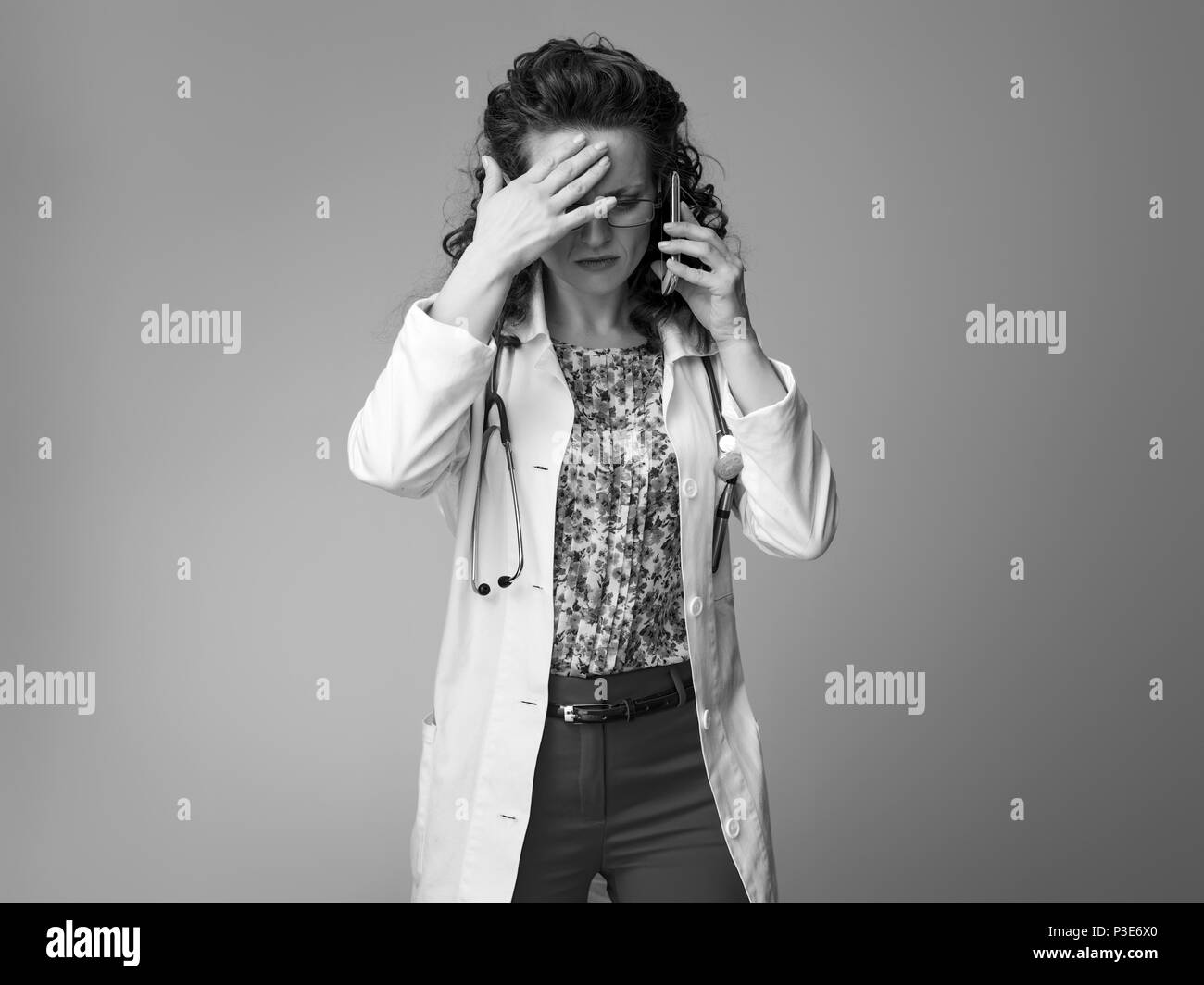 stressed paediatrician doctor in white medical robe using a cell phone isolated on Stock Photo