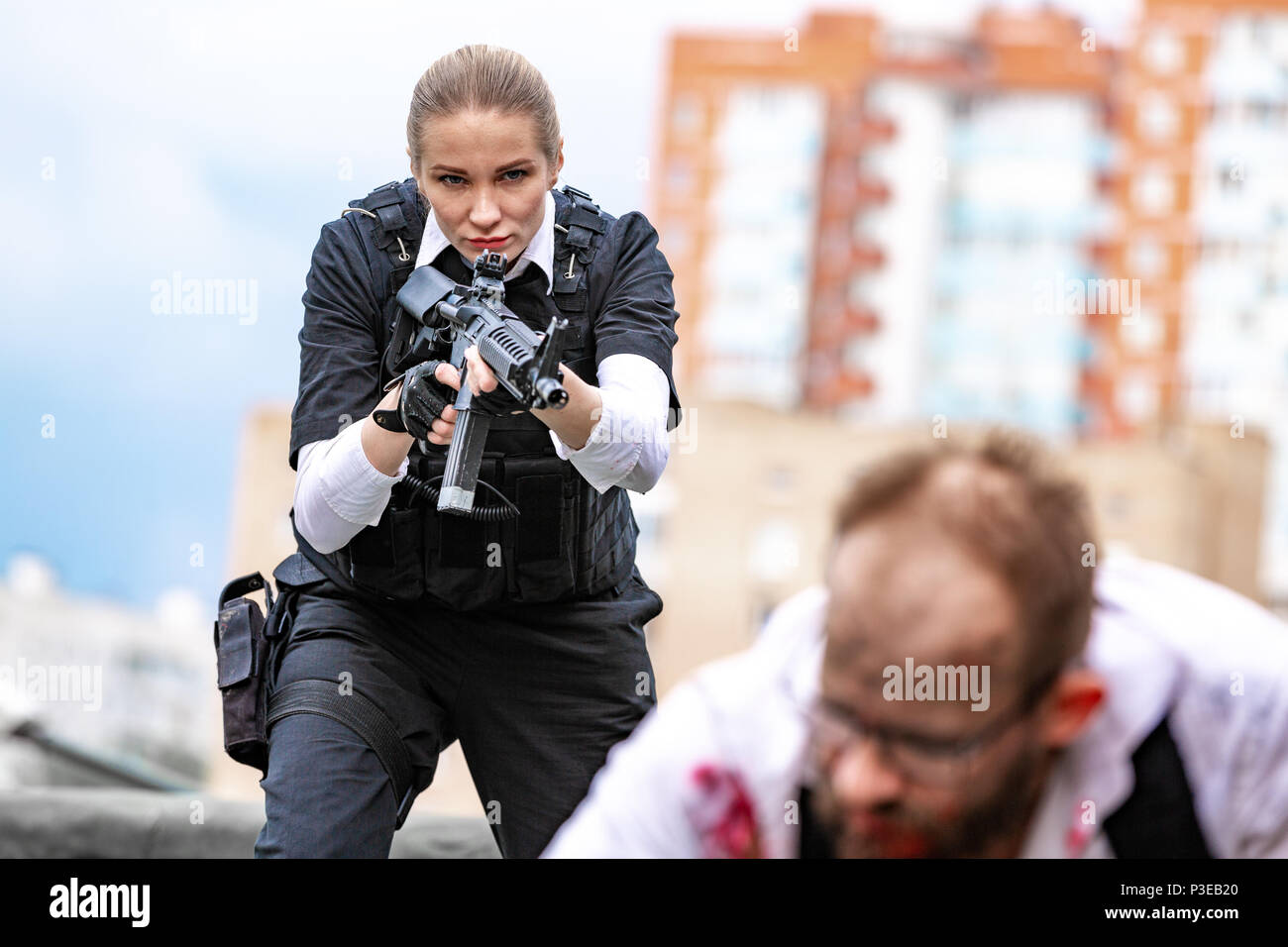 Woman soldier, spy agent killer or police woman with a gun in her hand holding at gunpoint a man lying on the ground Stock Photo