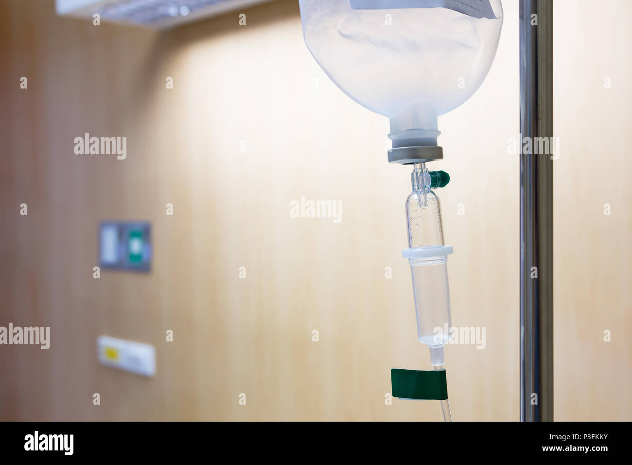 Close up saline solution drip for patient and infusion pump in hospital, with copy space wooden wall background at luxury VIP room. Stock Photo