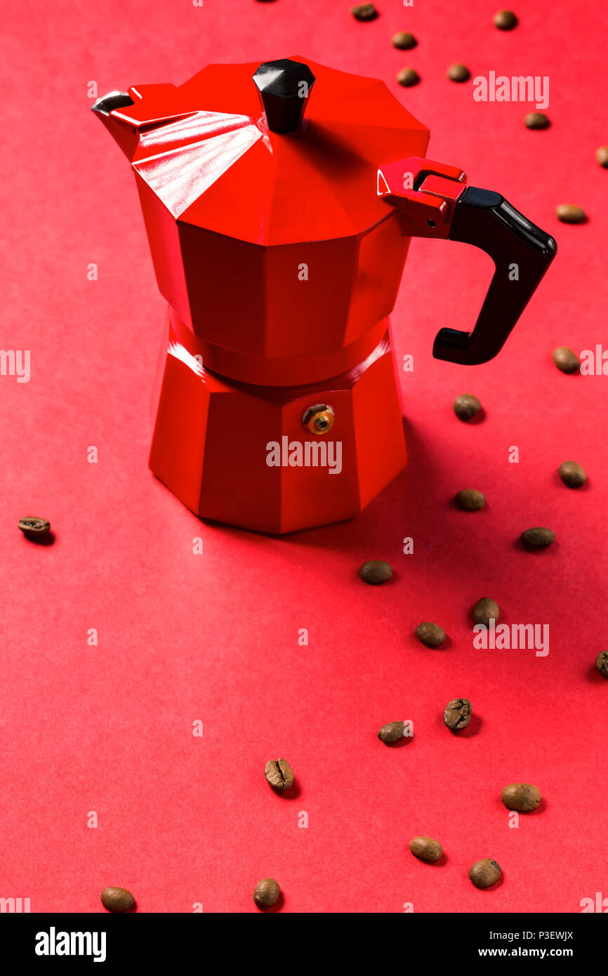 Red coffee maker and coffee beans on red background. Espresso Coffee