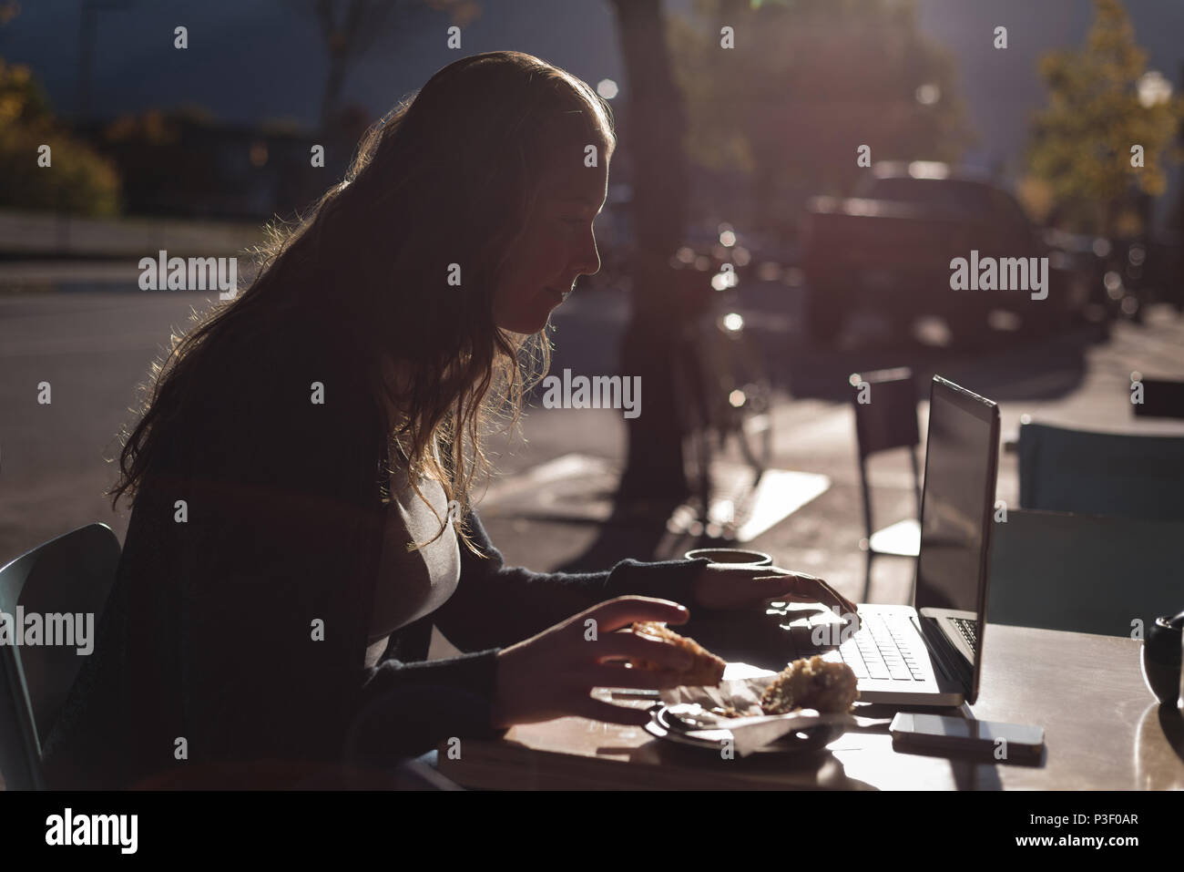 Woman using laptop while having breakfast Stock Photo