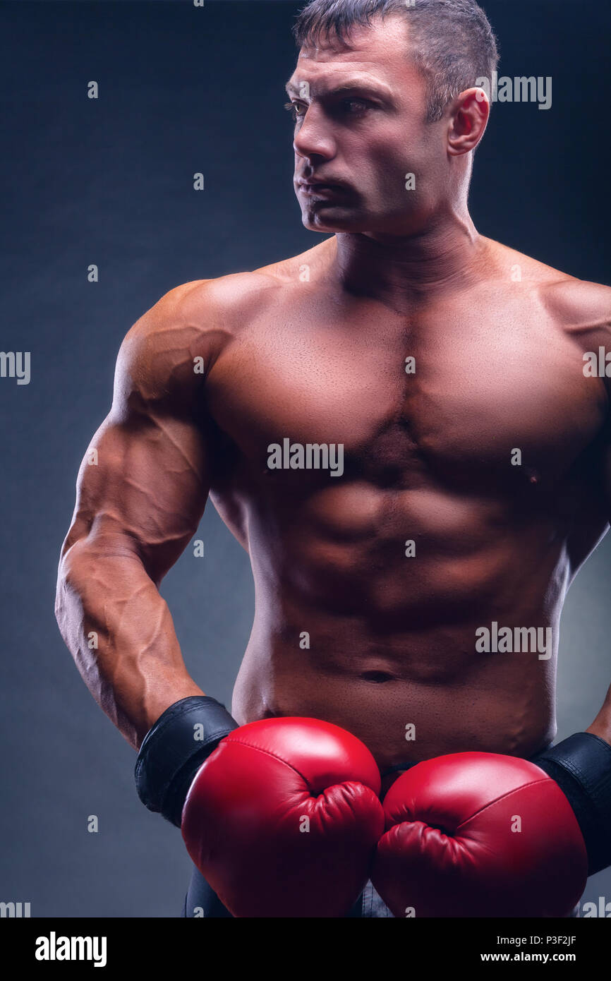 Boxing concept. Handsome boxer in red boxing gloves before a fight against a black background