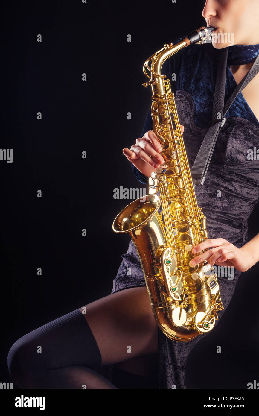 Saxophone player. Woman with saxophone against a dark background Stock Photo