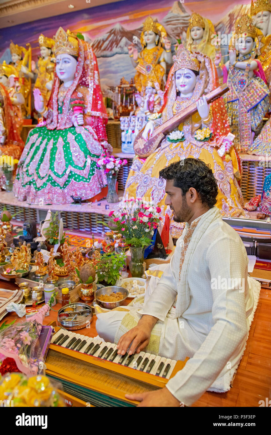 A pundit playing the harmonium & leading services at the Tulsi Mandir temple in South Richmond Hill, Queens, New York. Stock Photo