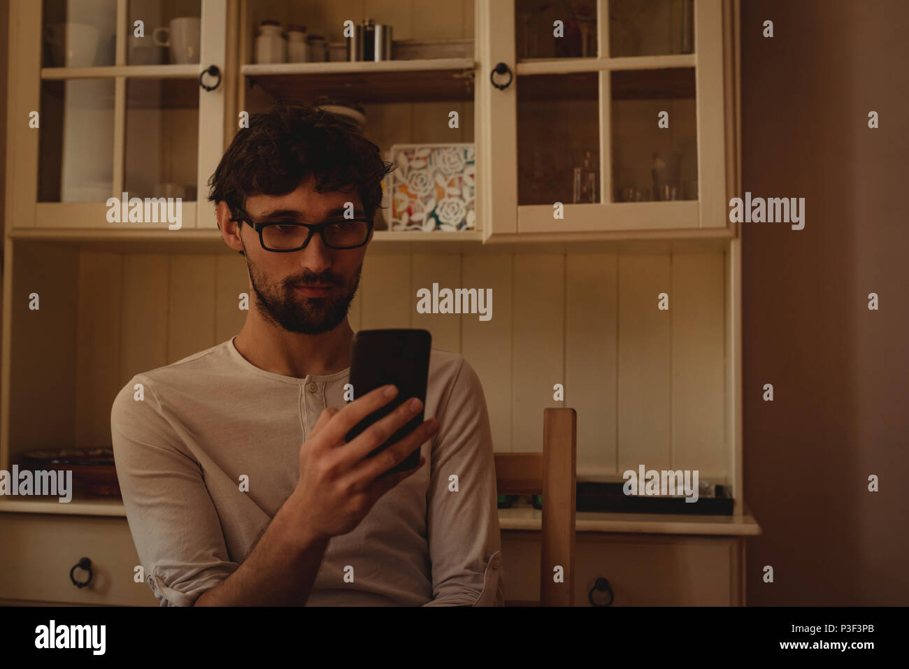 Man using mobile phone in kitchen Stock Photo