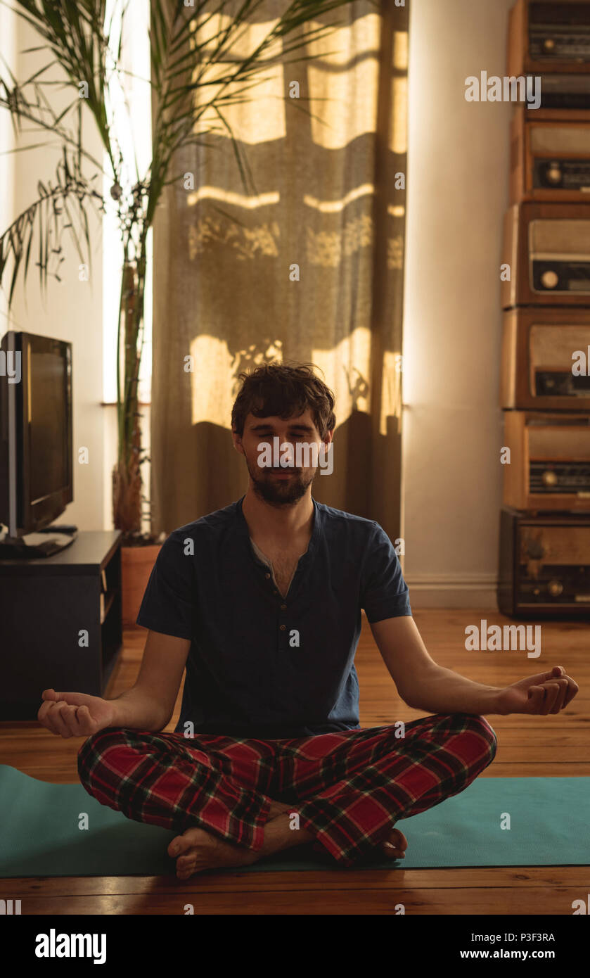 Man practicing yoga in living room Stock Photo