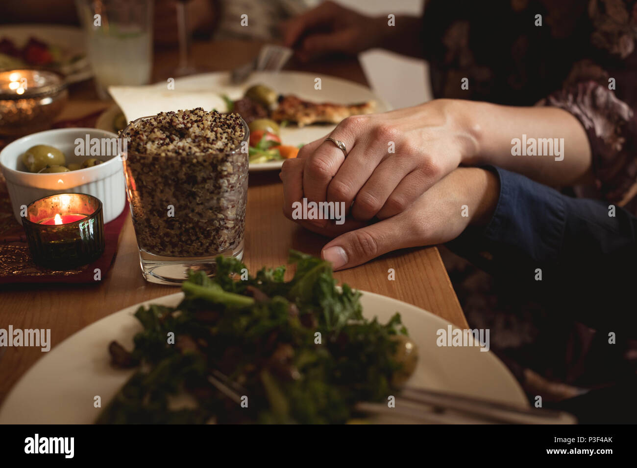 Couple holding hands while having meal Stock Photo