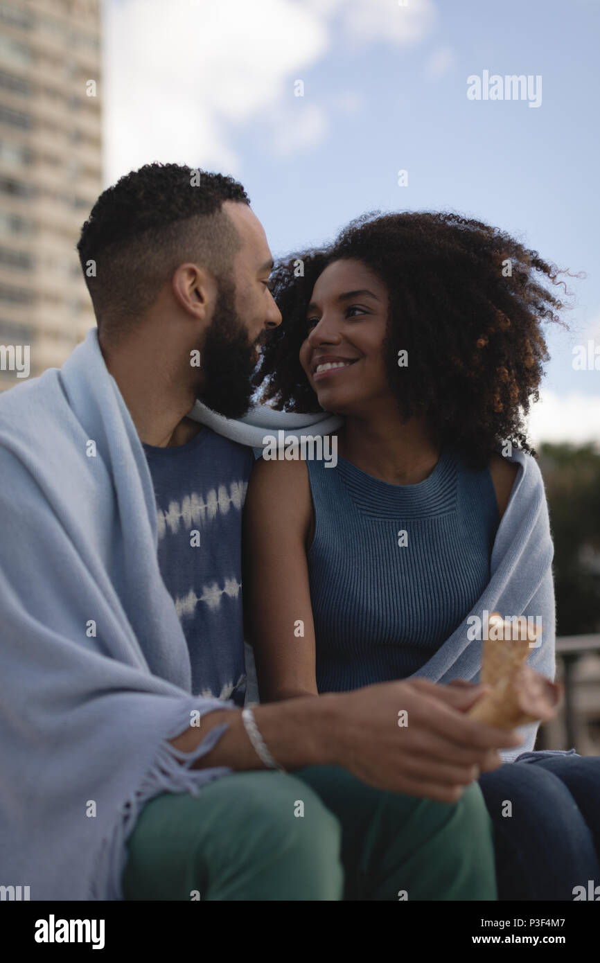 Couple wrapped in shawl looking at each other Stock Photo