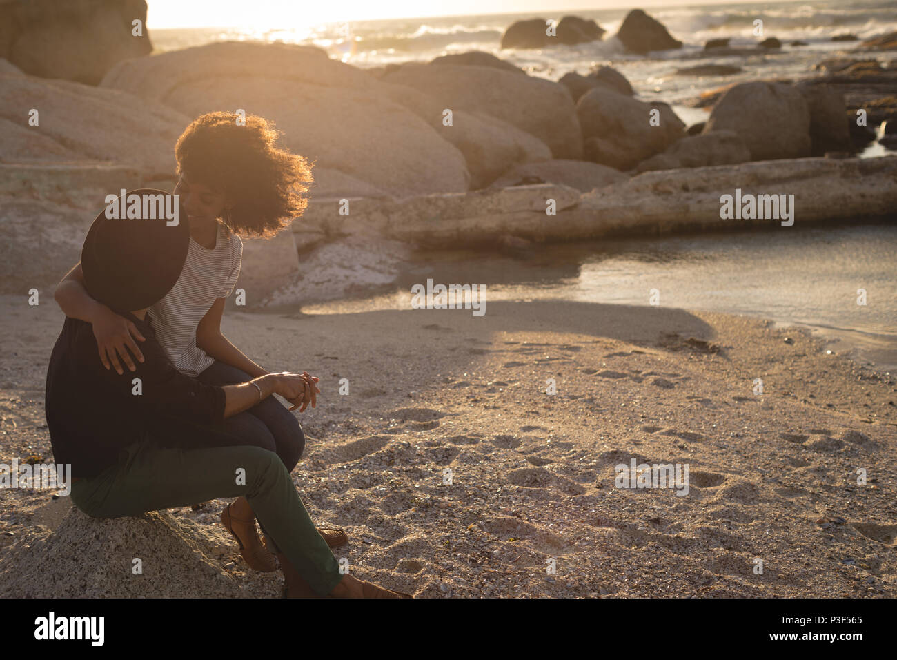 Couple looking at each other while sitting on beach Stock Photo
