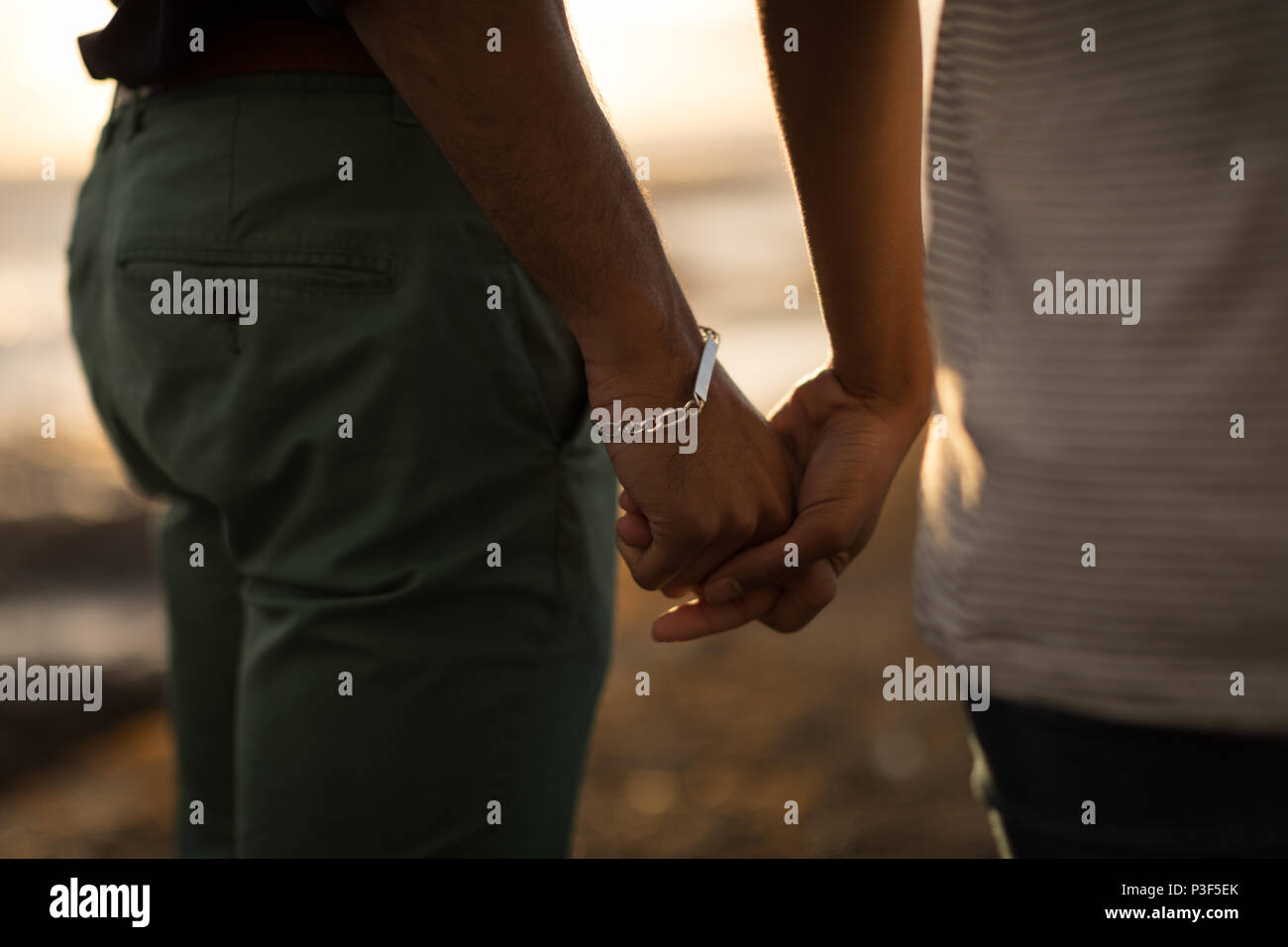 Couple holding hands in a beach during sunset Stock Photo