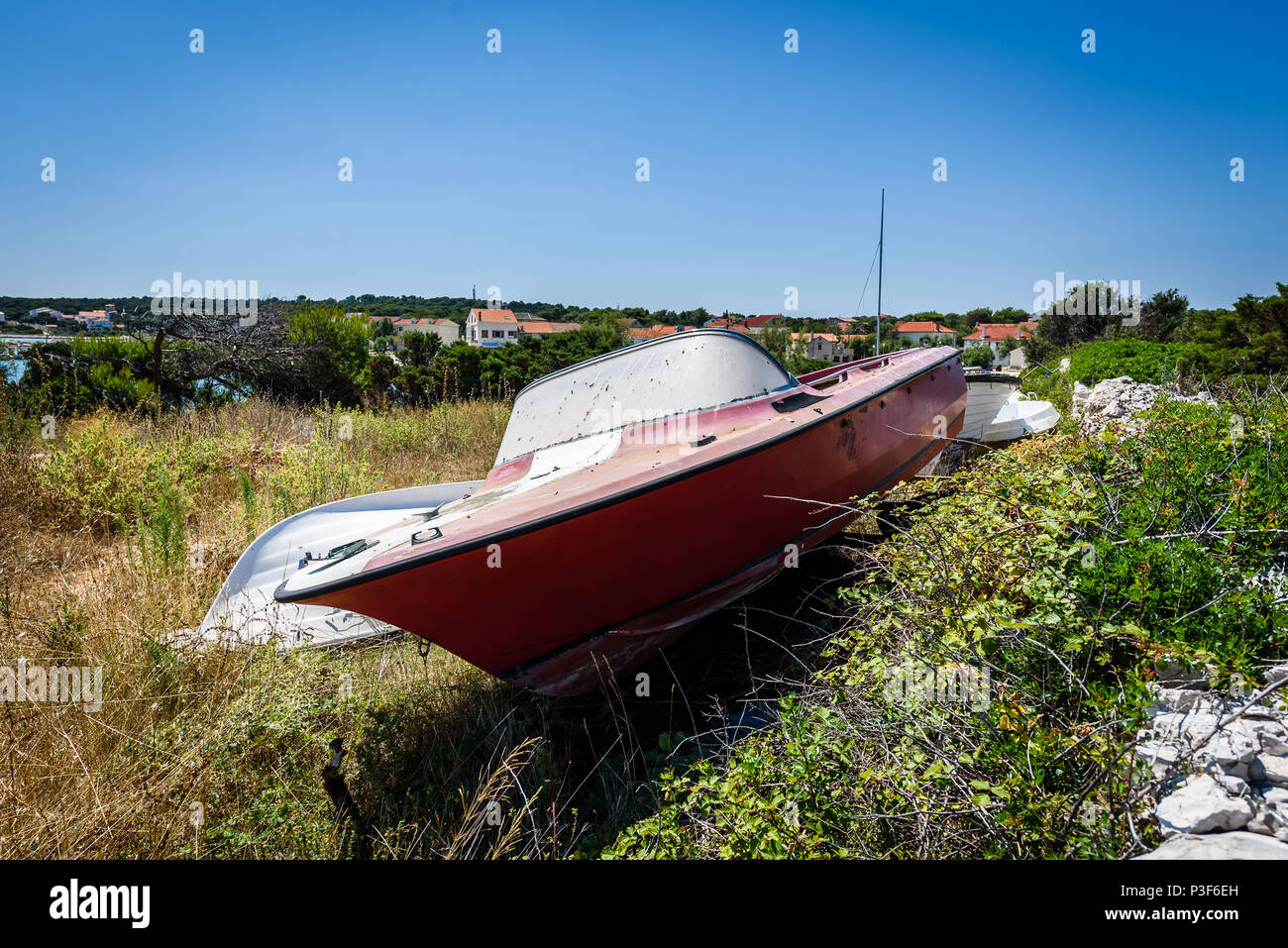 Old abandoned wrecked speed boat at ship or boat graveyard. Lots of different dry docked