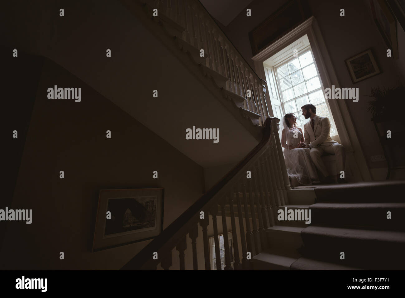 Bride and groom sitting on the window sill Stock Photo