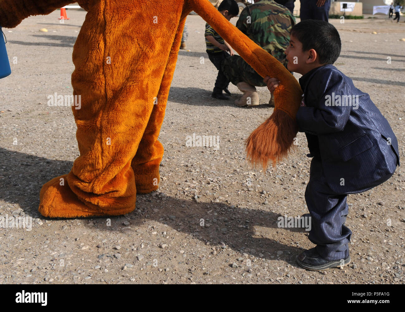 A young boy is anxious to  get the attention of The Lion of Kirkuk, portrayed by U.S. Army Spc. Brandon Smith, Mortar Platoon, Headquarters and Headquarters Company, 1st Battalion, 30th Infantry, 2nd Brigade Combat Team, 3rd Infantry Division, during a humanitarian aide drop at the Emergency Response Unit compound in Kirkuk, Iraq, Jan. 18. Soldiers from 1-30 IR and members of the Iraqi Emergency Response Unit teamed up to distribute food and supplies to 250 families from Adallah, one of the poorest villages in the province of Kirkuk. Stock Photo