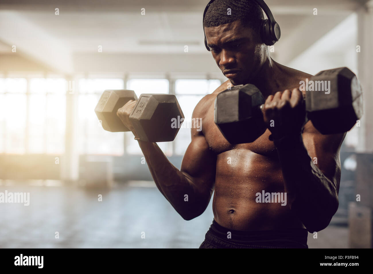 Bare chested man listening to music during workout at the gym. Athletic