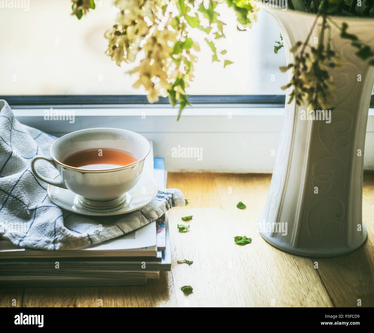 Cup of tea on window still with vase and flowers. Summer still life. Cozy home scene Stock Photo