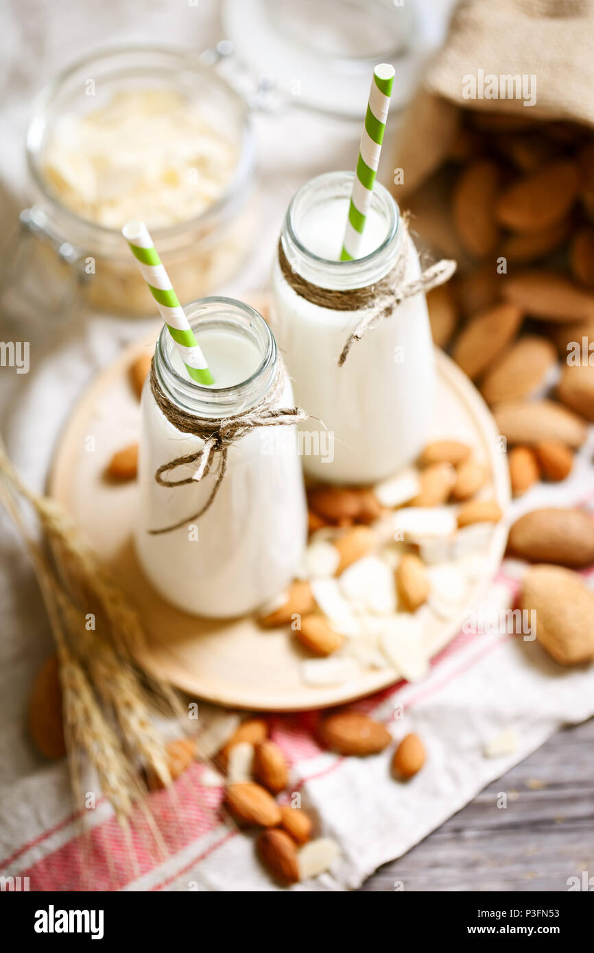 Almond and almond milk on a wooden table in the summer garden. Useful food. Stock Photo