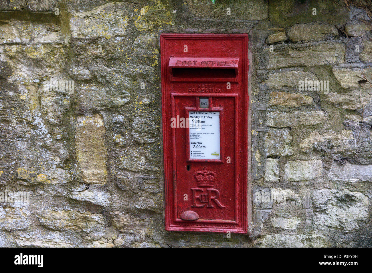 old red postbox displaying collection times and next collection built into a wall Stock Photo