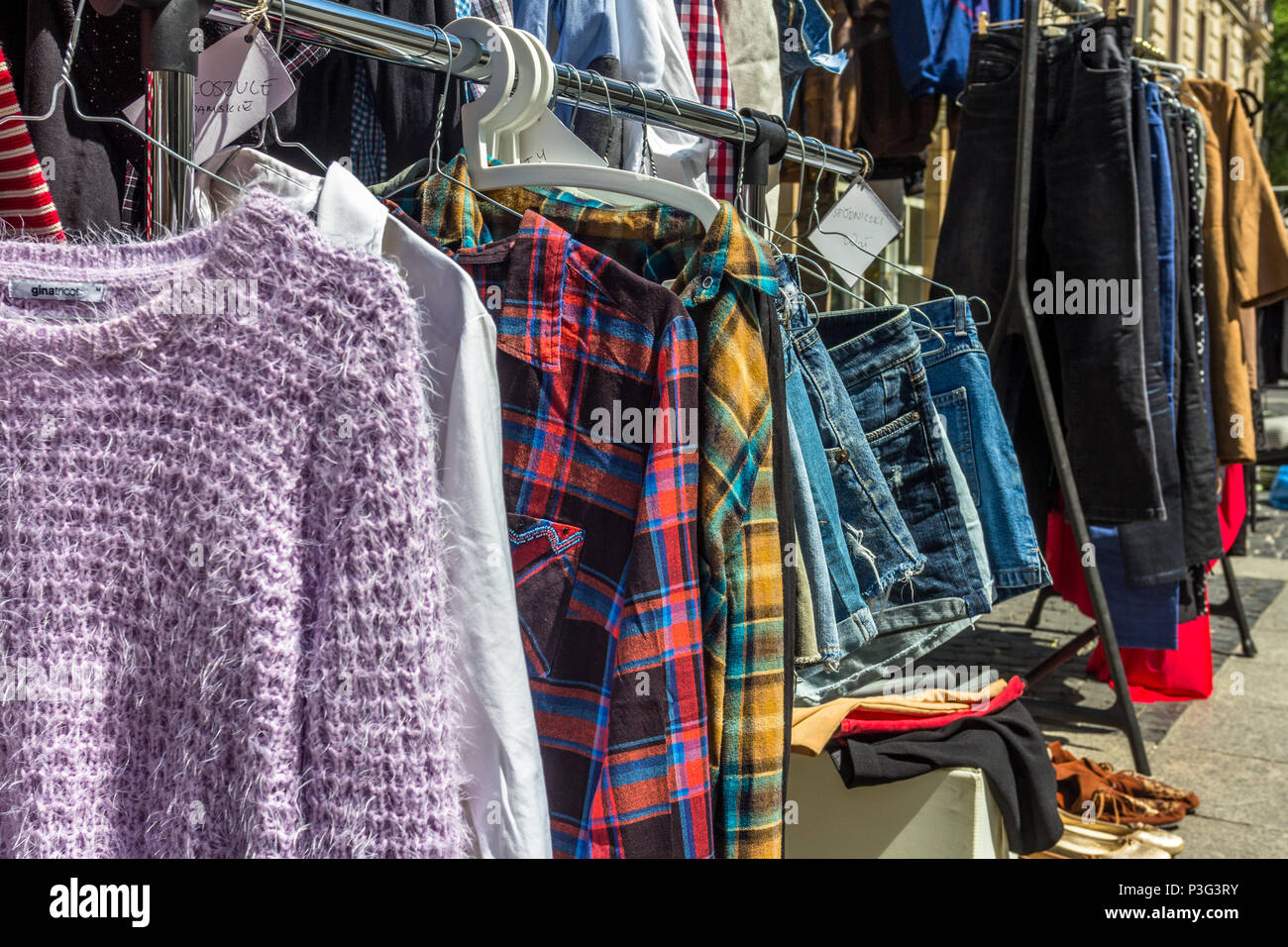 rail of second-hand clothes for sale at second-hand market in side street in Łódź, central Poland Stock Photo