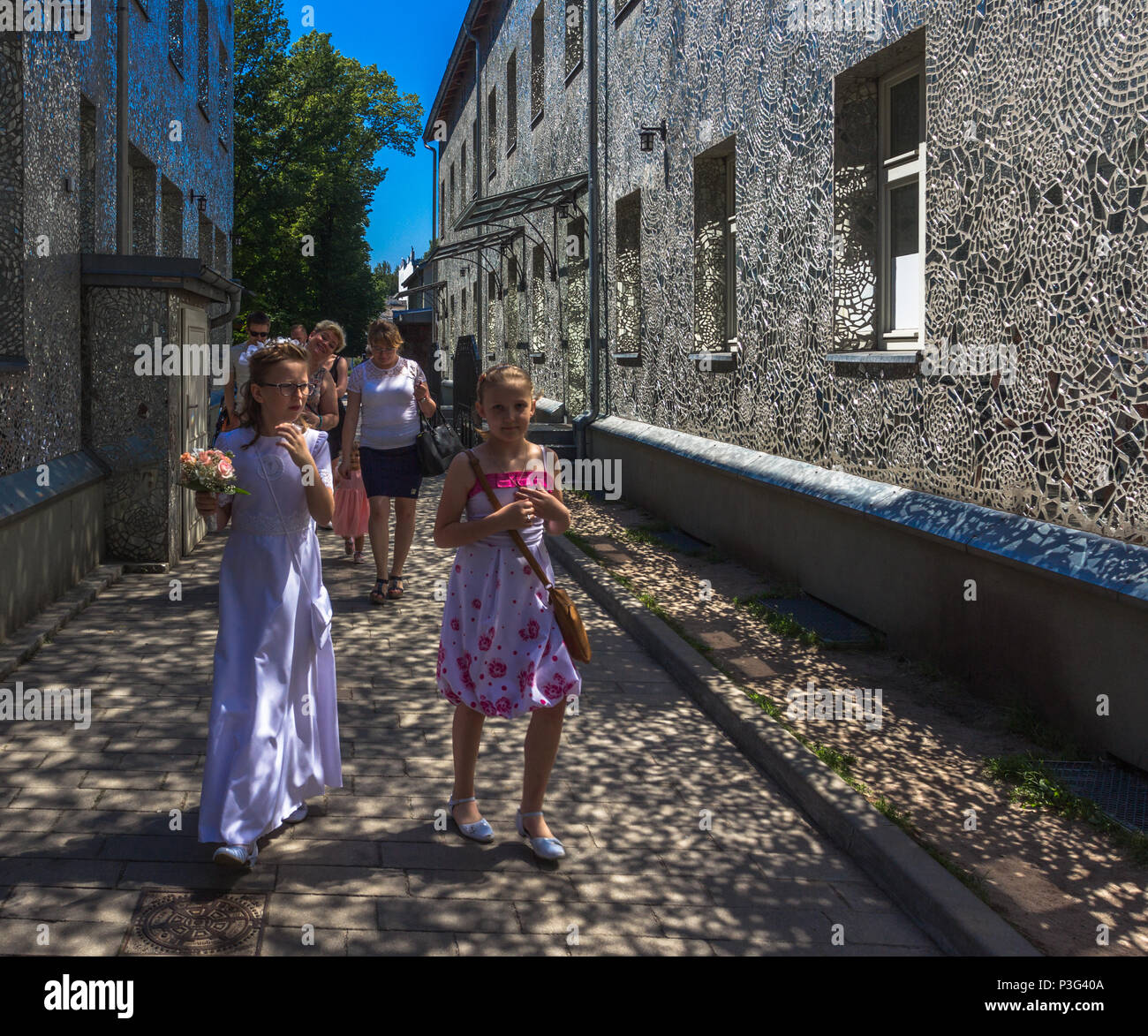 Family in Rosa's Passage, Łódź, Poland - a mosaic made up of small, irregular pieces of mirror on the facades of the houses Stock Photo