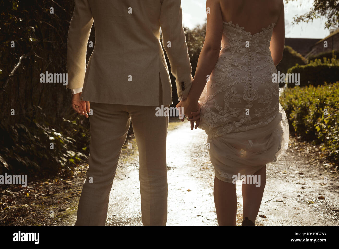Bride and groom walking hand in hand in the garden Stock Photo - Alamy