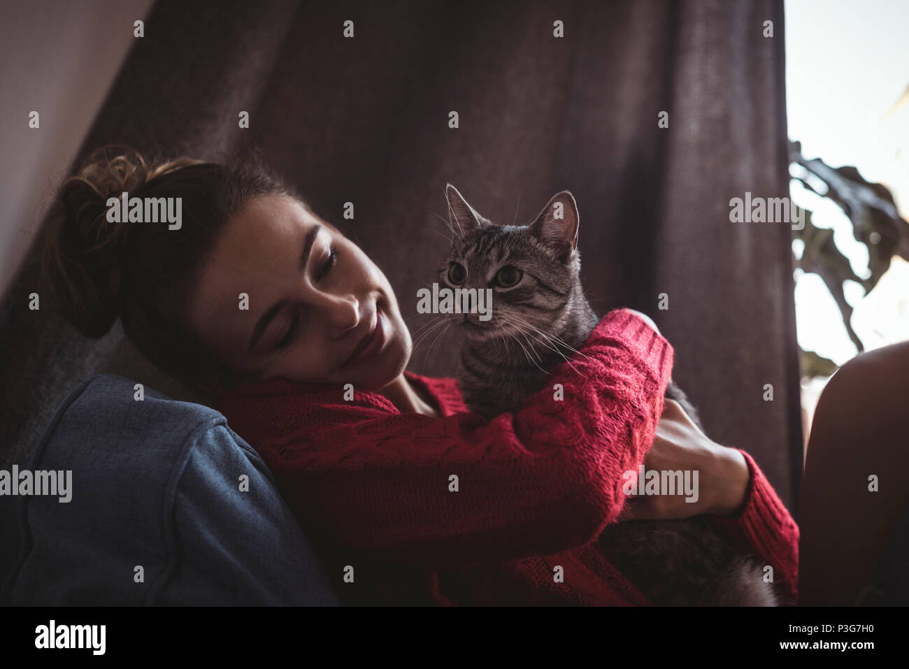 Smiling woman embracing her pet cat at home Stock Photo