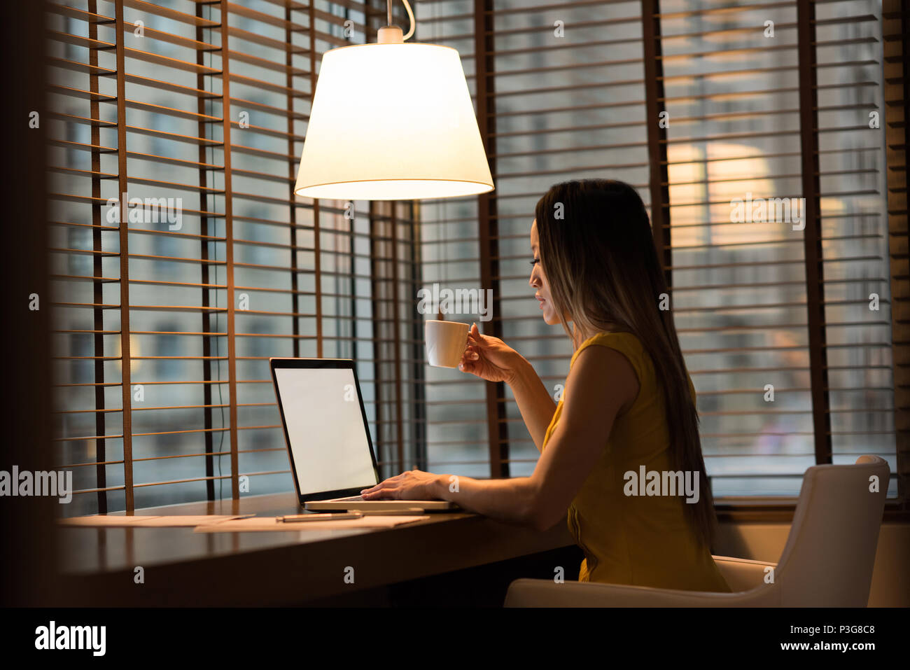 Businesswoman having coffee while working on laptop Stock Photo