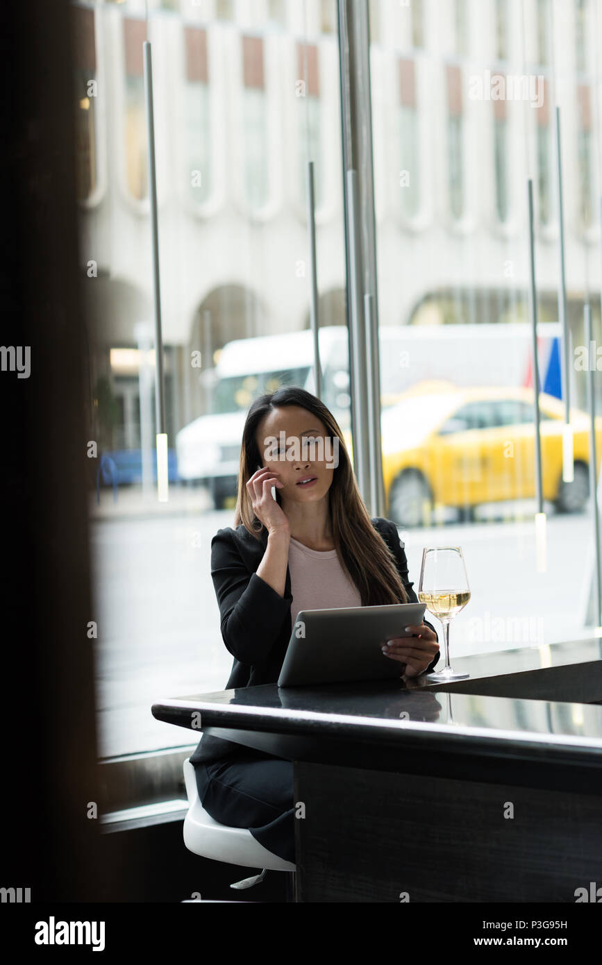 Businesswoman talking on phone while using her tablet Stock Photo