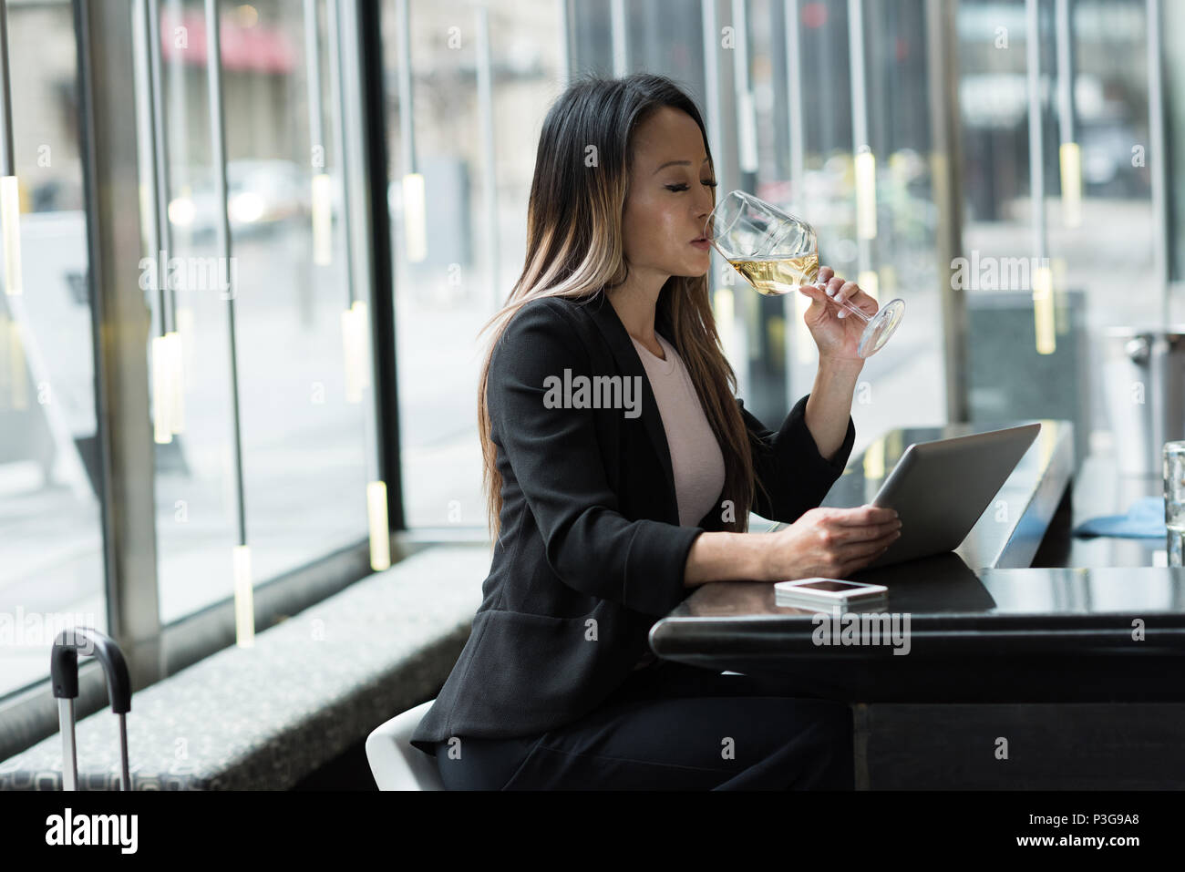 Businesswoman having champagne while working on tablet Stock Photo