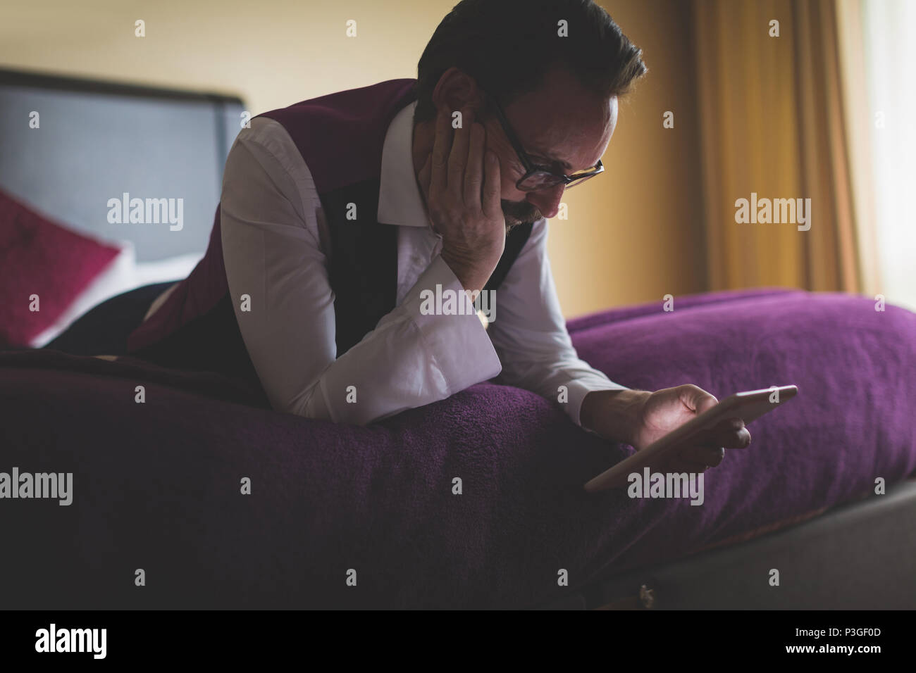 Businessman using digital tablet in bedroom Stock Photo