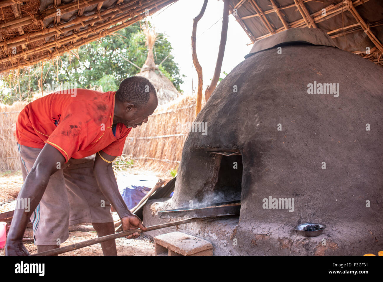 African man baking bread at an outdoor oven in Ethiopia, Homosa Stock