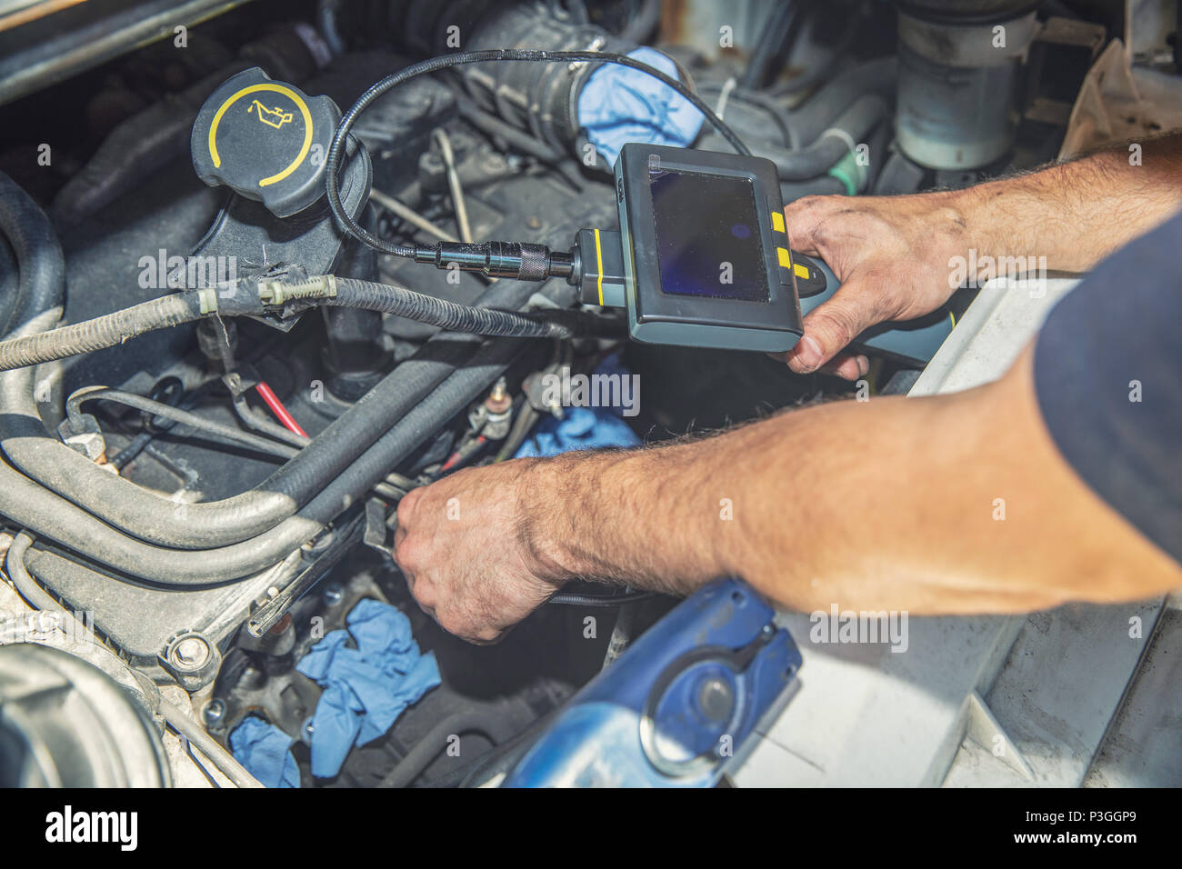 mechanic inspecting car engine with video borescope camera Stock Photo