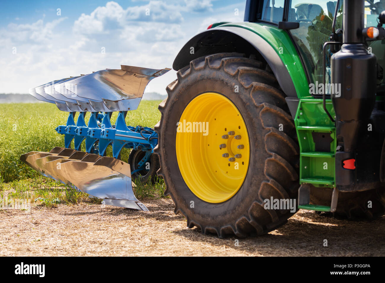 tractor with plough near the field Stock Photo