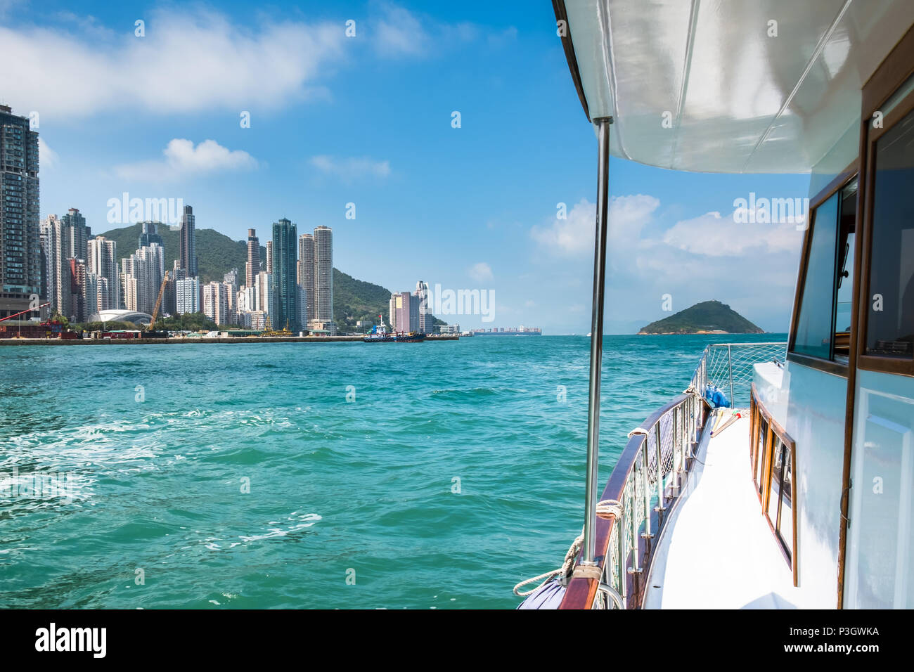 Pleasure boat moving across Victoria Harbour. Hong Kong Island is on left side . Wonderful weekend activities for friends. Perfect family getaway. Stock Photo