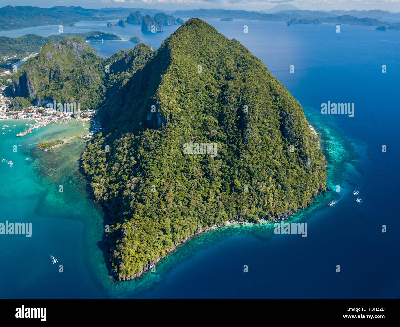 Aerial drone view of boats, coral reef and the town of El Nido in the Philippines Stock Photo
