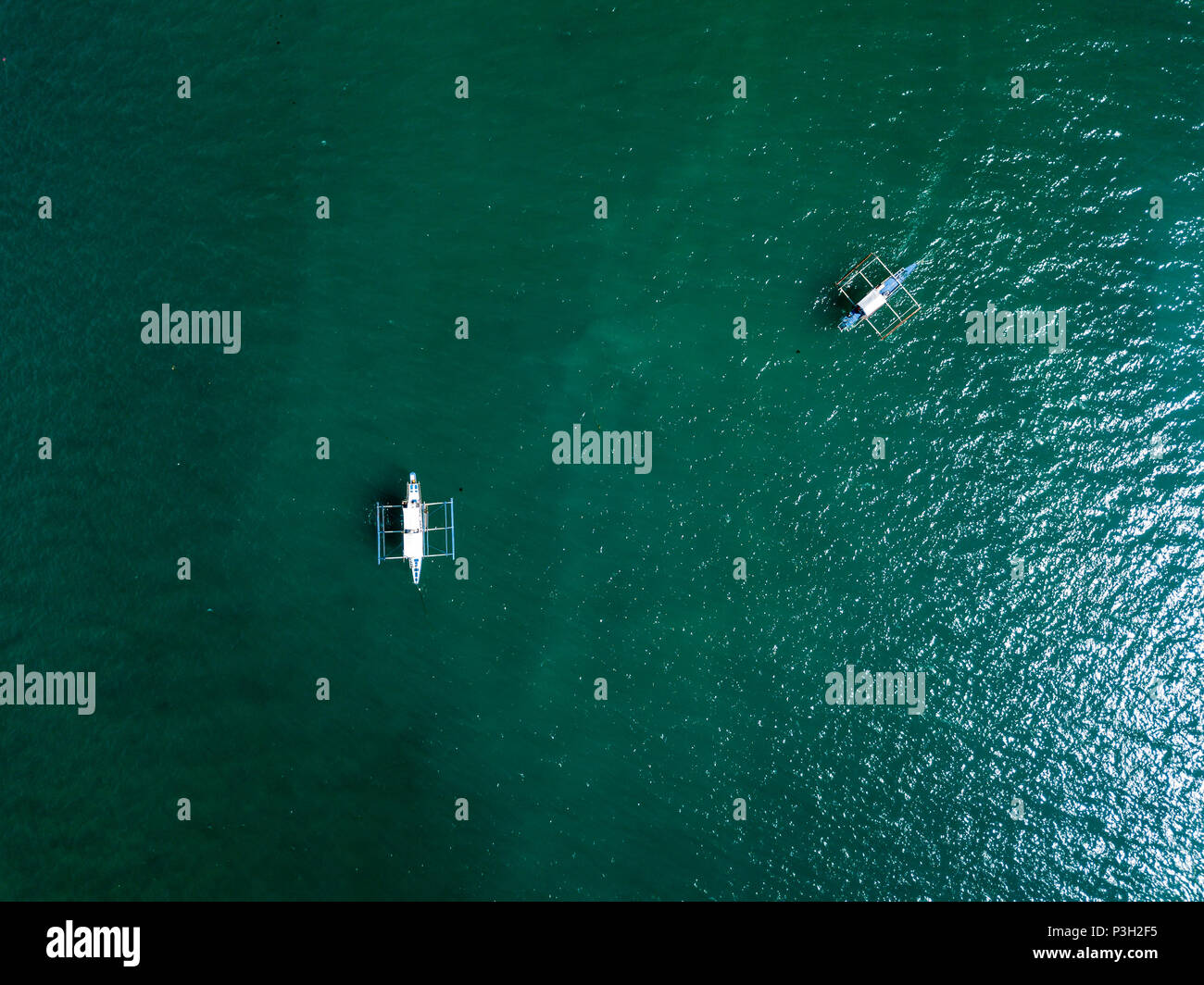 Top down aerial drown view of a small boat over a tropical coral reef in a clear ocean Stock Photo