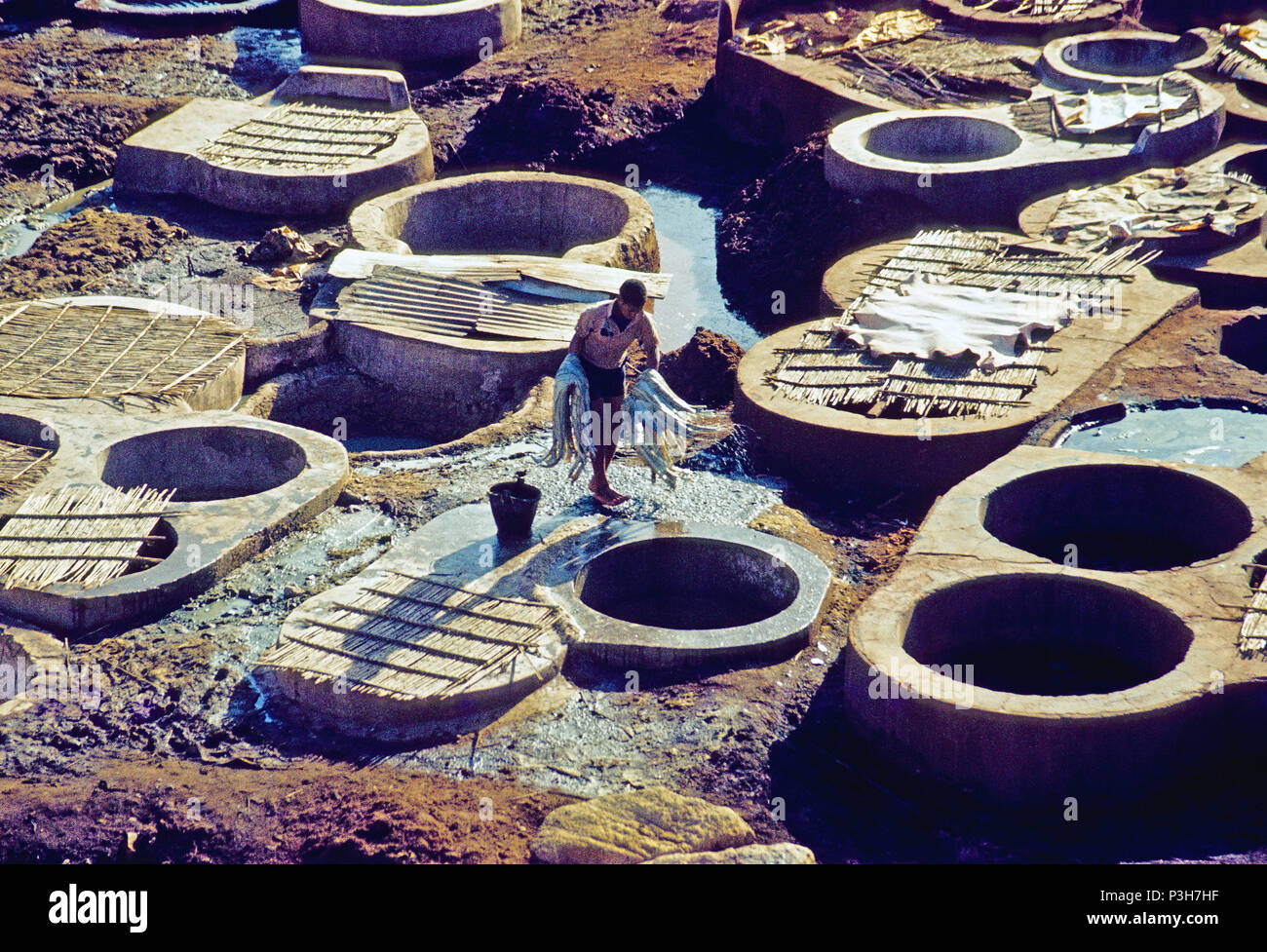 One worker carries animal hides from one tannery vat in the next. In the old town of Fes, visitors can take a look at the work in leather tanneries. For centuries, animal hides with bird dung stain and natural alkalis have been processed into finished leather in traditional way in pits in the ground and clay basins, analogue undated image from March 1985. Photo: Matthias Toedt/dpa-Zentralbild/ZB/Picture Alliance | usage worldwide Stock Photo