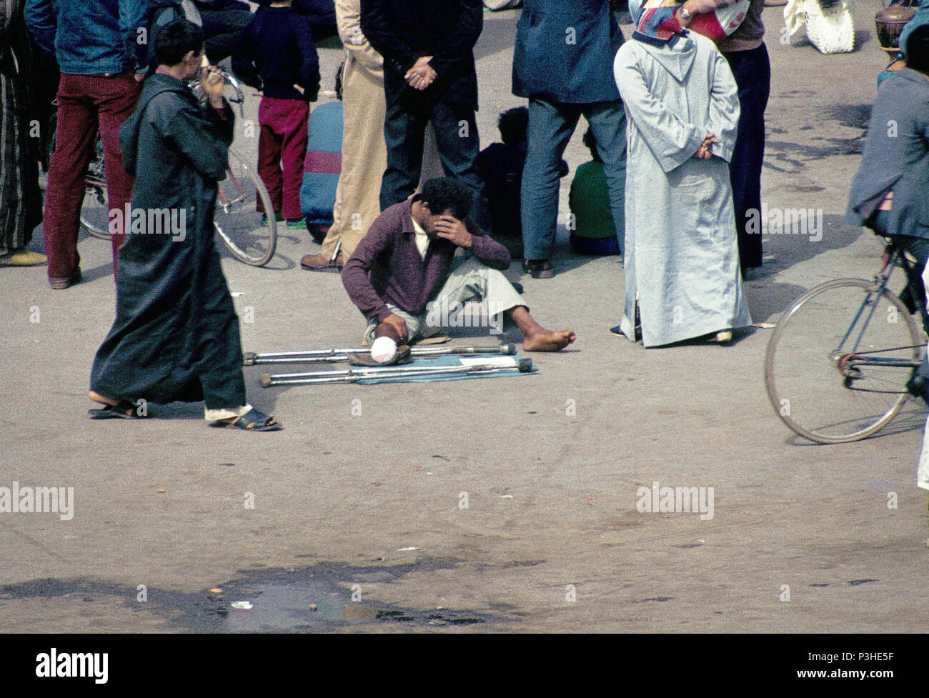 Leg amputee young beggar in the central market square Djemaa el Fna in Marrakech, unnoticed by the bystanders, analogue undated image of March 1985. Photo: Matthias Toedt/dpa-Zentralbild/ZB/Picture Alliance | usage worldwide Stock Photo