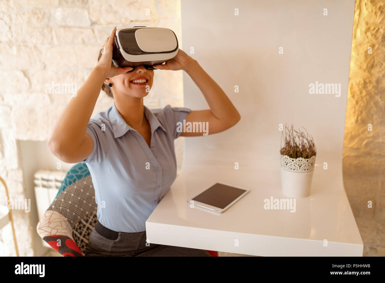 Smiling businesswoman using virtual reality glasses in a cafe. Stock Photo